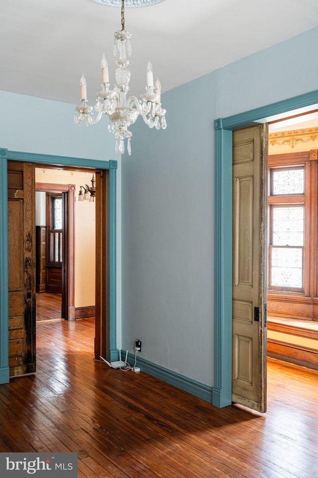 unfurnished dining area with baseboards, a wealth of natural light, and wood finished floors