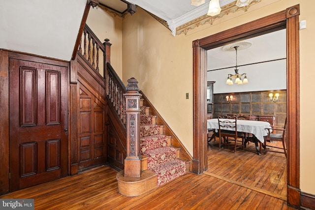 interior space featuring baseboards, ornamental molding, wood finished floors, and an inviting chandelier