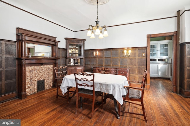 dining space featuring dark wood-style floors, a wainscoted wall, visible vents, ornamental molding, and a chandelier