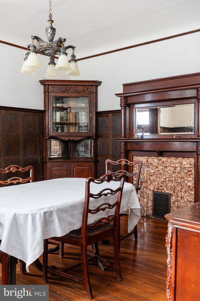 dining area with a chandelier, wainscoting, wood finished floors, and visible vents