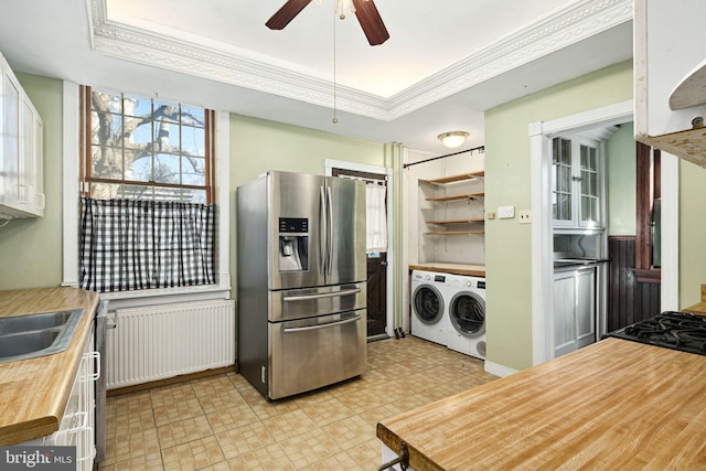 kitchen with stainless steel fridge, independent washer and dryer, a tray ceiling, light countertops, and white cabinetry