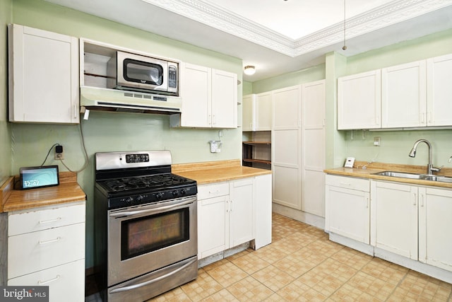 kitchen featuring stainless steel appliances, range hood, white cabinetry, and a sink