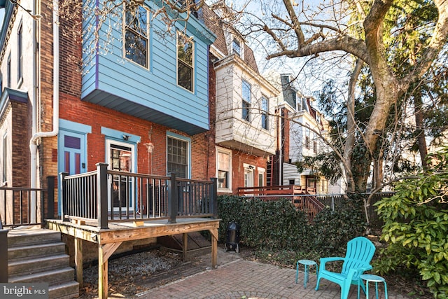 rear view of house with a patio area, a wooden deck, and brick siding