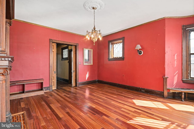 unfurnished dining area with baseboards, an inviting chandelier, and wood finished floors