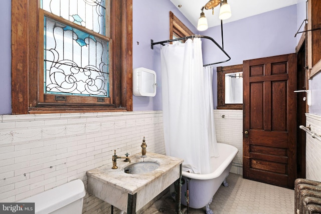 bathroom with wainscoting, a sink, tile walls, and toilet