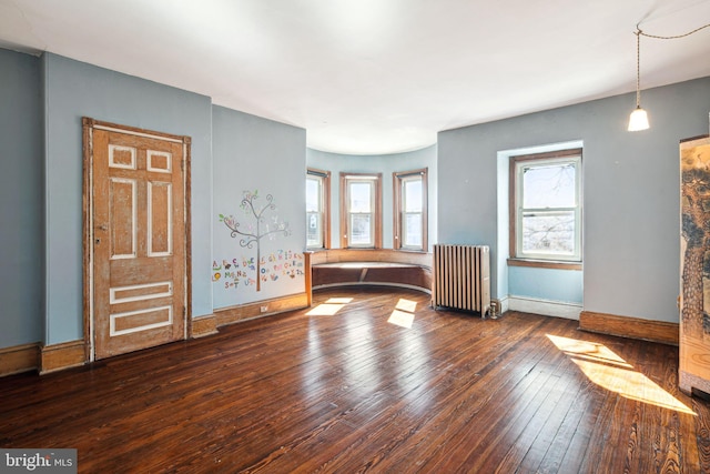 interior space with baseboards, a healthy amount of sunlight, dark wood finished floors, and radiator heating unit