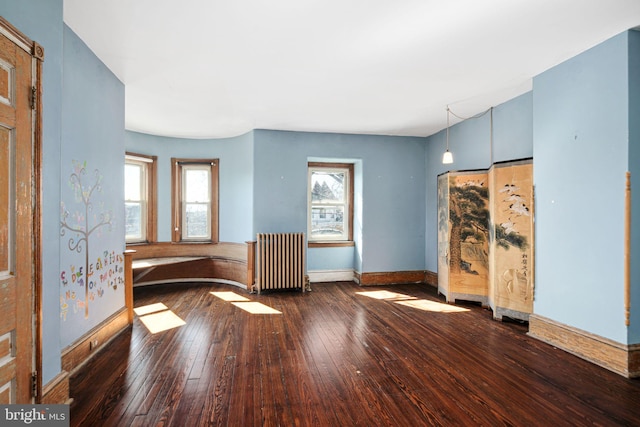 interior space with radiator heating unit, baseboards, and wood finished floors