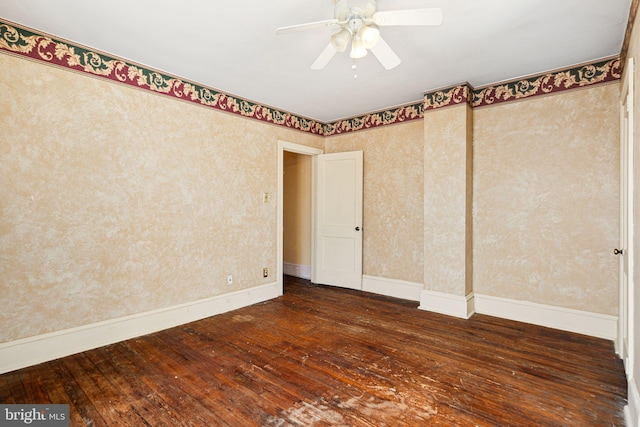 empty room featuring dark wood-style floors, ceiling fan, baseboards, and wallpapered walls