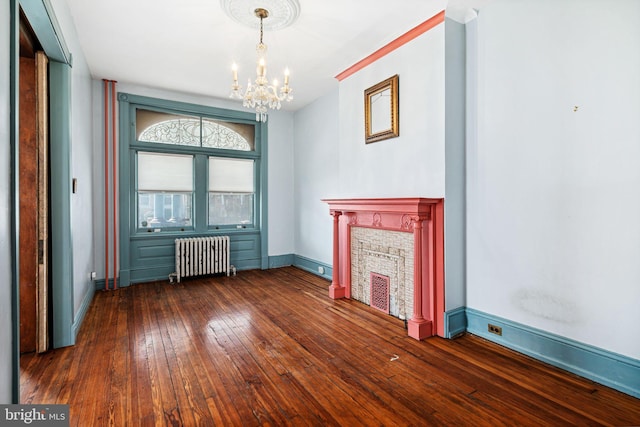 unfurnished living room featuring a notable chandelier, dark wood-type flooring, a fireplace, baseboards, and radiator