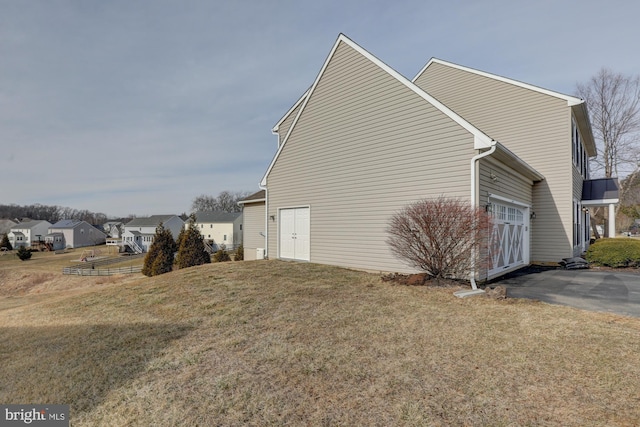 view of side of property with a garage, a lawn, and driveway