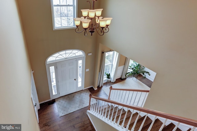 entryway with baseboards, dark wood-type flooring, an inviting chandelier, stairs, and a high ceiling