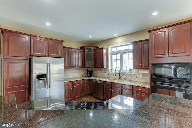 kitchen with black appliances, glass insert cabinets, dark stone counters, and a sink