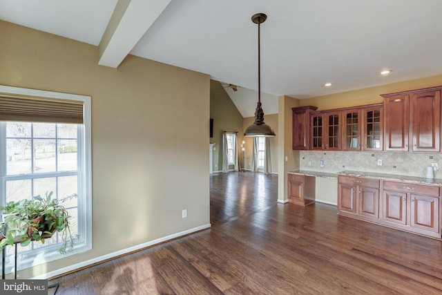 kitchen featuring light stone counters, dark wood-type flooring, tasteful backsplash, glass insert cabinets, and pendant lighting