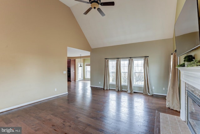 unfurnished living room with ceiling fan, high vaulted ceiling, wood finished floors, a fireplace with flush hearth, and baseboards