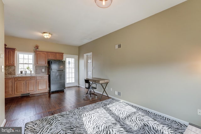 kitchen featuring visible vents, light countertops, freestanding refrigerator, decorative backsplash, and dark wood finished floors