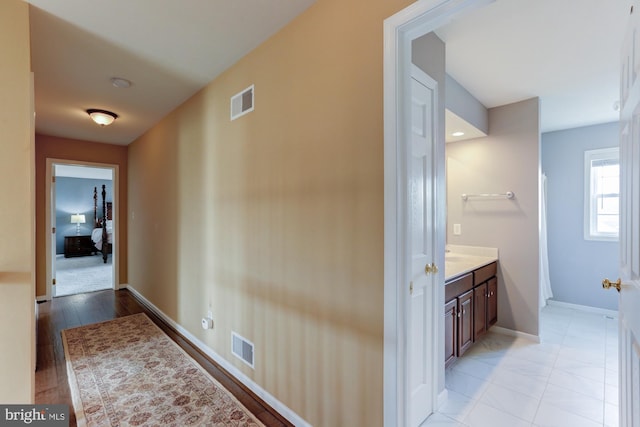 hallway with visible vents and baseboards