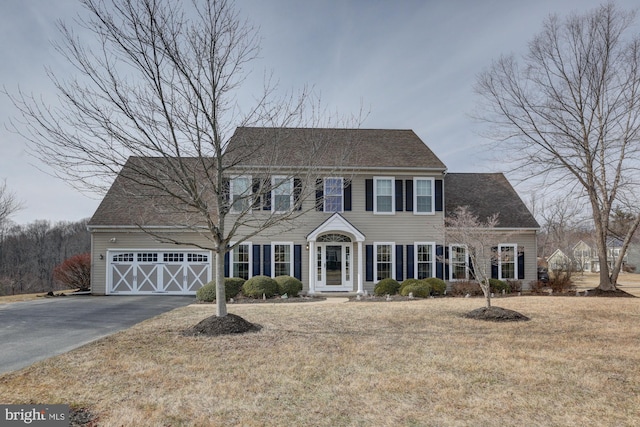 colonial home with a garage, a front lawn, and aphalt driveway