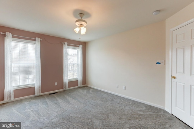 spare room featuring baseboards, visible vents, and light colored carpet