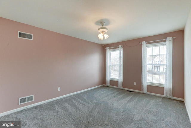 carpeted spare room with visible vents and baseboards