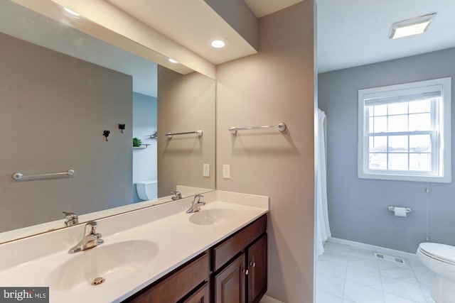 full bathroom featuring toilet, double vanity, visible vents, and a sink