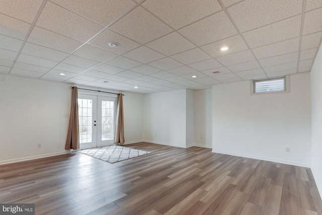 spare room featuring french doors, light wood finished floors, recessed lighting, a paneled ceiling, and baseboards