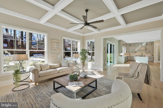 living room with a healthy amount of sunlight, coffered ceiling, and light hardwood / wood-style flooring