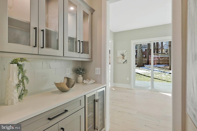 bar featuring wine cooler, backsplash, and light hardwood / wood-style floors