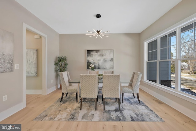 dining space featuring a healthy amount of sunlight, light hardwood / wood-style flooring, and a notable chandelier