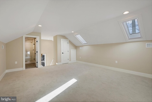 bonus room with vaulted ceiling with skylight and light carpet