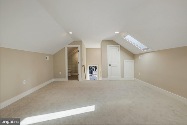 bonus room with lofted ceiling with skylight and light colored carpet