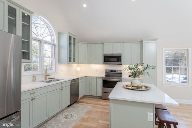 kitchen with a breakfast bar, stainless steel appliances, light stone countertops, light hardwood / wood-style floors, and decorative backsplash