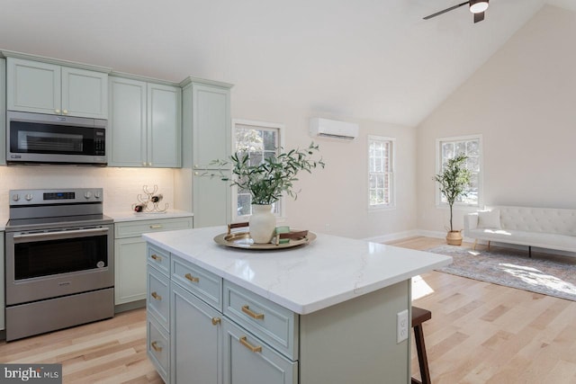 kitchen featuring stainless steel appliances, a center island, light stone counters, and light hardwood / wood-style floors