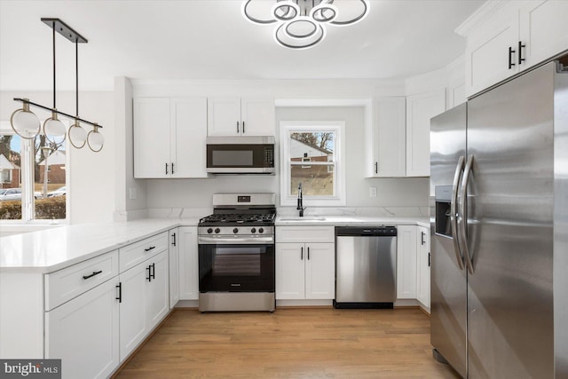 kitchen featuring sink, white cabinets, hanging light fixtures, kitchen peninsula, and stainless steel appliances