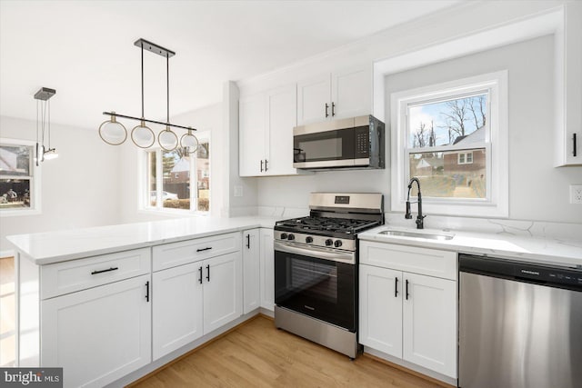 kitchen with pendant lighting, sink, stainless steel appliances, white cabinets, and kitchen peninsula