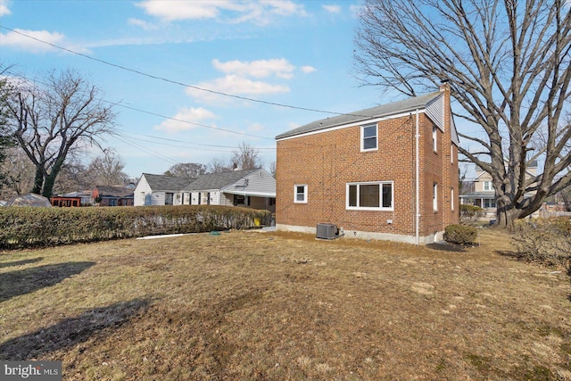 back of house with central AC and a lawn