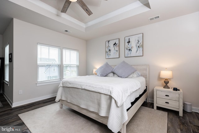 bedroom featuring dark wood-type flooring, ceiling fan, lofted ceiling, and a raised ceiling