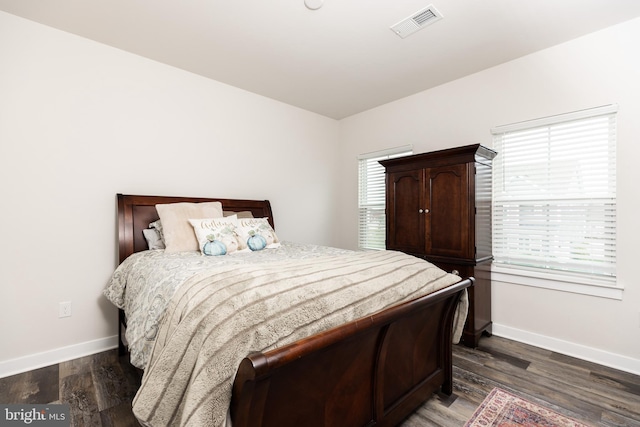 bedroom with multiple windows and dark wood-type flooring