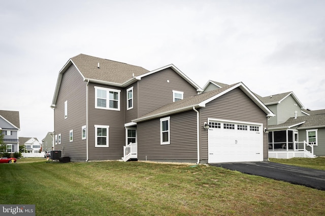 exterior space with cooling unit, a garage, and a front lawn