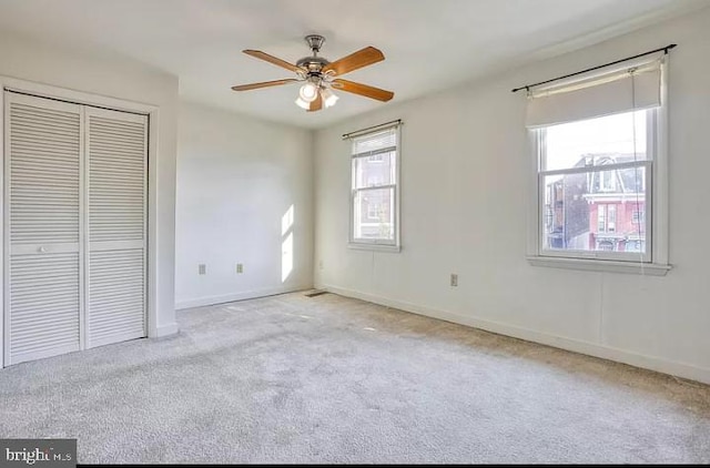 unfurnished bedroom featuring ceiling fan, a closet, and light carpet