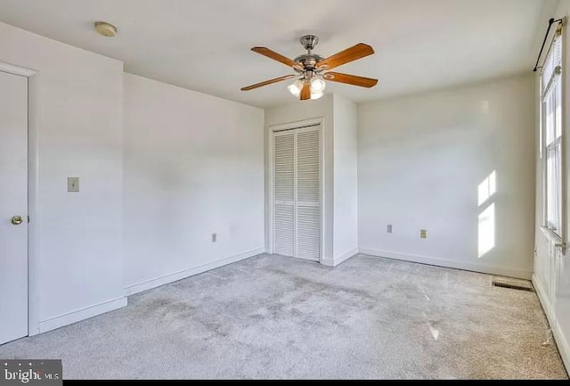 unfurnished bedroom featuring light colored carpet, a closet, and ceiling fan