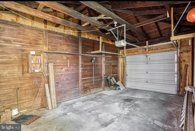 garage featuring a garage door opener and wooden walls