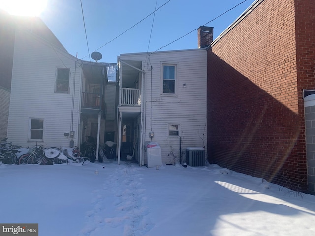 snow covered house featuring central AC unit