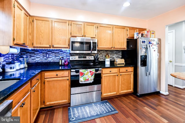 kitchen with tasteful backsplash, appliances with stainless steel finishes, dark stone countertops, and dark hardwood / wood-style flooring