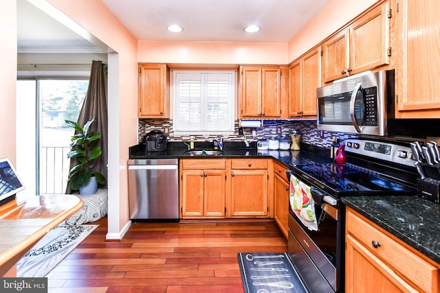 kitchen with hardwood / wood-style flooring, a healthy amount of sunlight, appliances with stainless steel finishes, and sink