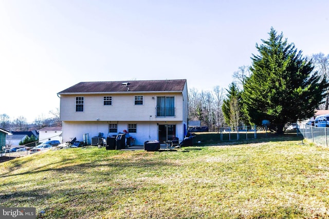 rear view of property featuring a trampoline and a lawn