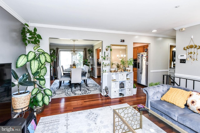 living room featuring an inviting chandelier, ornamental molding, and dark hardwood / wood-style floors