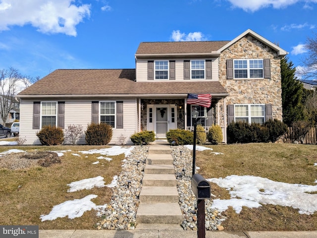 front facade featuring covered porch and a front yard