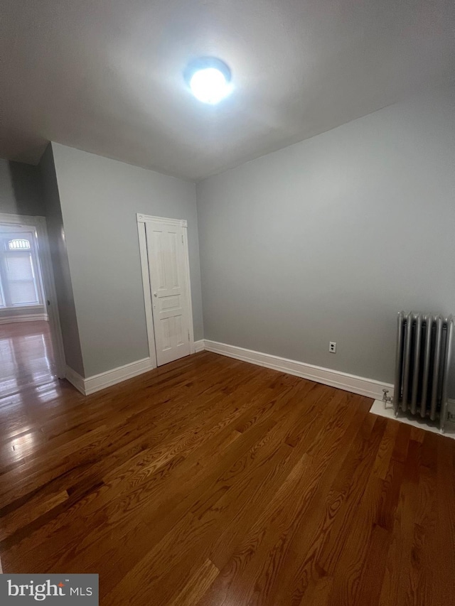 unfurnished room with hardwood / wood-style flooring and radiator heating unit