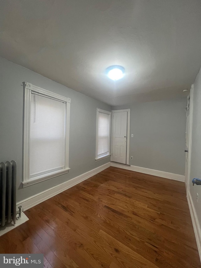 spare room featuring radiator heating unit and dark hardwood / wood-style floors