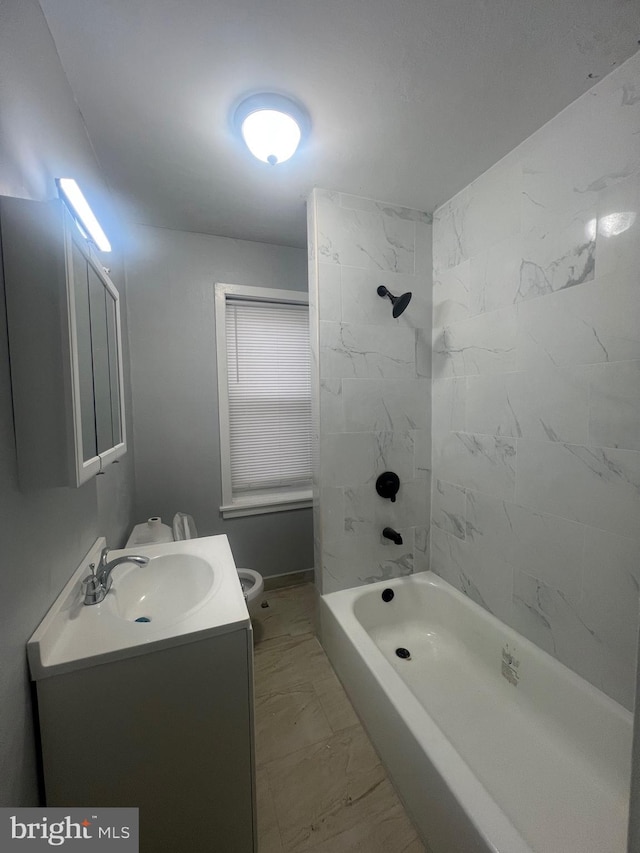 full bathroom featuring tiled shower / bath, vanity, and toilet